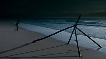 Movie still from “When Dinosaurs Ruled the Earth” (1970), directed by Val Guest – An umbrella on the beach at night with the ocean in the background; Extreme Wide shot, High angle