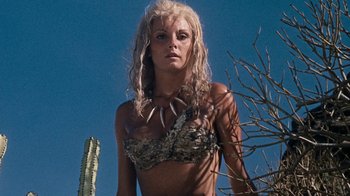 Movie still from “When Dinosaurs Ruled the Earth” (1970), directed by Val Guest – A woman with long blonde hair wearing a camouflage bikini; Close Up shot, Low angle