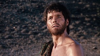 Movie still from “When Dinosaurs Ruled the Earth” (1970), directed by Val Guest – A man with a beard is standing in the dirt; Close Up shot, Low angle