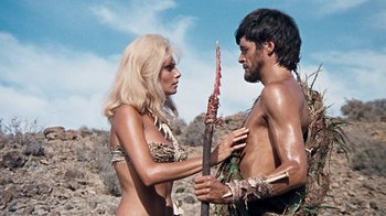 Movie still from “When Dinosaurs Ruled the Earth” (1970), directed by Val Guest – A man and a woman are holding a spear; Medium shot, Over the shoulder angle
