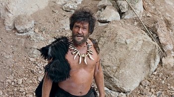 Movie still from “When Dinosaurs Ruled the Earth” (1970), directed by Val Guest – A man with a bunch of animal teeth on his chest; Medium shot, Low angle