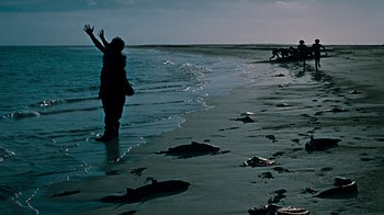 Movie still from “When Dinosaurs Ruled the Earth” (1970), directed by Val Guest – A woman standing on a beach near the ocean; Extreme Wide shot, High angle