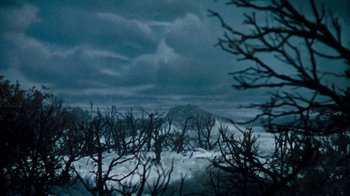 Movie still from “When Dinosaurs Ruled the Earth” (1970), directed by Val Guest – A view of trees and a snowy hill in the distance; Extreme Wide shot, High angle