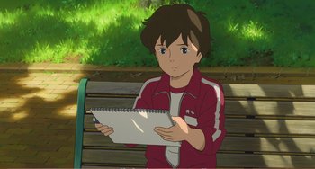 Movie still from “When Marnie Was There” (2014), directed by Hiromasa Yonebayashi – A boy is sitting on a park bench holding a notebook; Medium shot, High angle