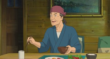 Movie still from “When Marnie Was There” (2014), directed by Hiromasa Yonebayashi – An animated man sitting at a table with a bowl of food in front of him; Medium shot, High angle