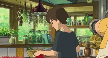 Movie still from “When Marnie Was There” (2014), directed by Hiromasa Yonebayashi – A boy in a kitchen with a basket of fruit; Medium shot, Over the shoulder angle
