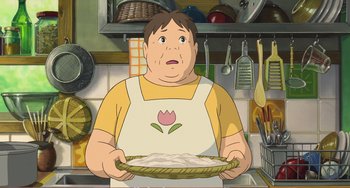 Movie still from “When Marnie Was There” (2014), directed by Hiromasa Yonebayashi – A cartoon of a man holding a pie in a kitchen; Medium shot, Low angle