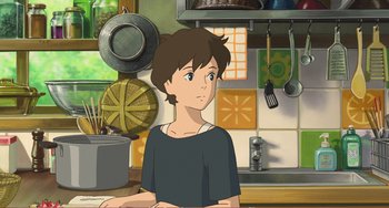 Movie still from “When Marnie Was There” (2014), directed by Hiromasa Yonebayashi – A boy is standing in a kitchen with a pan on the counter; Medium shot, Over the shoulder angle