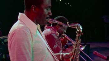 Movie still from “When We Were Kings” (1996), directed by Leon Gast – A couple of people that are playing some instruments; Medium shot, Low angle
