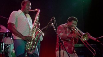 Movie still from “When We Were Kings” (1996), directed by Leon Gast – A couple of people that are playing some instruments; Medium shot, Low angle