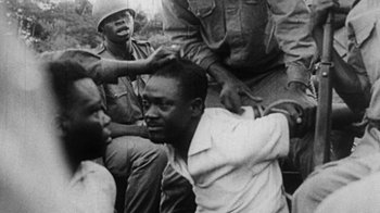 Movie still from “When We Were Kings” (1996), directed by Leon Gast – A black and white photo of a man being shaved by a soldier; Close Up shot, High angle