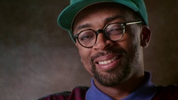 Movie still from “When We Were Kings” (1996), directed by Leon Gast – A person wearing glasses and a hat; Close Up shot, Over the shoulder angle