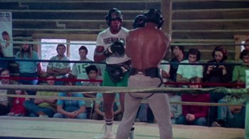 Movie still from “When We Were Kings” (1996), directed by Leon Gast – Two boxers in a boxing ring with spectators watching; Wide shot, Over the shoulder angle