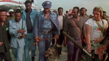 Movie still from “When We Were Kings” (1996), directed by Leon Gast – A group of men walking a dog down a street; Medium shot, Low angle