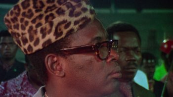 Movie still from “When We Were Kings” (1996), directed by Leon Gast – A person wearing glasses and a leopard print hat; Close Up shot, Low angle