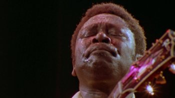 Movie still from “When We Were Kings” (1996), directed by Leon Gast – A person holding a guitar; Extreme Close Up shot, Low angle