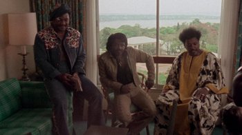 Movie still from “When We Were Kings” (1996), directed by Leon Gast – A group of people sitting next to each other in front of a window; Wide shot, Low angle