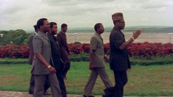 Movie still from “When We Were Kings” (1996), directed by Leon Gast – A group of men walking down a sidewalk; Medium shot, Low angle