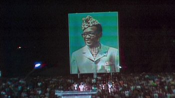 Movie still from “When We Were Kings” (1996), directed by Leon Gast – An image of a man on a large screen; Medium shot, Low angle