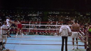 Movie still from “When We Were Kings” (1996), directed by Leon Gast – A man standing in front of a crowd in a boxing ring; Wide shot, High angle
