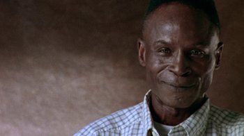Movie still from “When We Were Kings” (1996), directed by Leon Gast – An older man wearing a checkered button up shirt; Close Up shot, Low angle