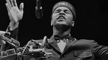 Movie still from “When We Were Kings” (1996), directed by Leon Gast – A black and white photo of a man singing; Close Up shot, Low angle