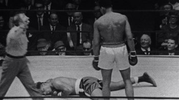 Movie still from “When We Were Kings” (1996), directed by Leon Gast – An old photo of a man in a boxing ring; Medium shot, Overhead angle