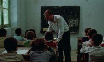 Movie still from “Where Is the Friend's House?” (1987), directed by Abbas Kiarostami – A man standing in front of a group of children; Medium shot, Over the shoulder angle