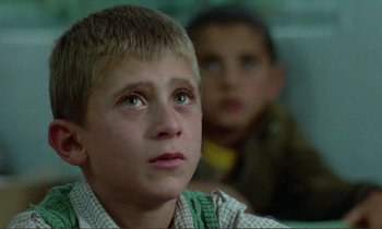 Movie still from “Where Is the Friend's House?” (1987), directed by Abbas Kiarostami – A young boy looking up at something in the distance; Close Up shot, High angle