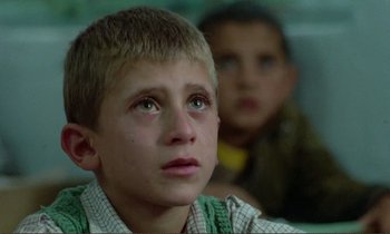 Movie still from “Where Is the Friend's House?” (1987), directed by Abbas Kiarostami – A young boy looking up at the sky; Close Up shot, High angle