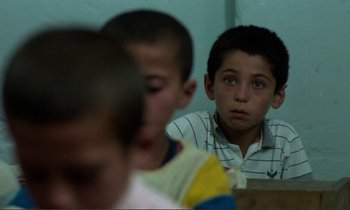 Movie still from “Where Is the Friend's House?” (1987), directed by Abbas Kiarostami – A group of young boys sitting at a table; Close Up shot, Over the shoulder angle