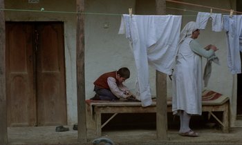Movie still from “Where Is the Friend's House?” (1987), directed by Abbas Kiarostami – A young boy is sitting on a wooden bench; Wide shot, High angle