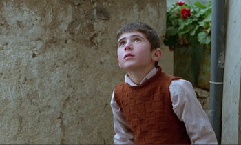 Movie still from “Where Is the Friend's House?” (1987), directed by Abbas Kiarostami – A young boy looking up at the sky; Medium shot, Low angle