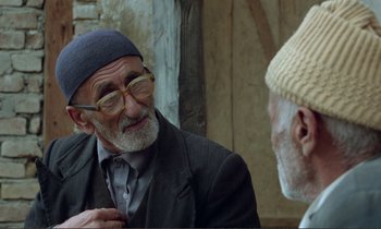 Movie still from “Where Is the Friend's House?” (1987), directed by Abbas Kiarostami – Two older men talking to each other outside; Close Up shot, Over the shoulder angle