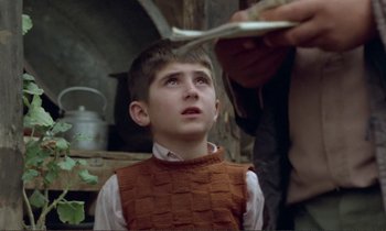 Movie still from “Where Is the Friend's House?” (1987), directed by Abbas Kiarostami – A young boy getting his hair cut by an older man; Close Up shot, Over the shoulder angle