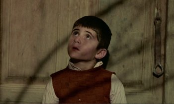 Movie still from “Where Is the Friend's House?” (1987), directed by Abbas Kiarostami – A young boy looking up into the air; Medium shot, High angle