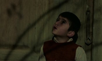 Movie still from “Where Is the Friend's House?” (1987), directed by Abbas Kiarostami – A young boy looking up into the air; Close Up shot, High angle