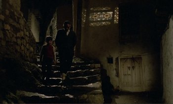 Movie still from “Where Is the Friend's House?” (1987), directed by Abbas Kiarostami – A man and a boy walking up some stairs; Wide shot, High angle