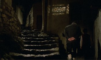 Movie still from “Where Is the Friend's House?” (1987), directed by Abbas Kiarostami – A man walking down a set of stairs; Wide shot, High angle