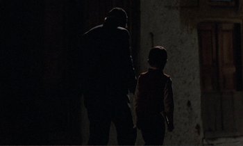 Movie still from “Where Is the Friend's House?” (1987), directed by Abbas Kiarostami – A man and a child are walking in the dark; Medium shot, Over the shoulder angle
