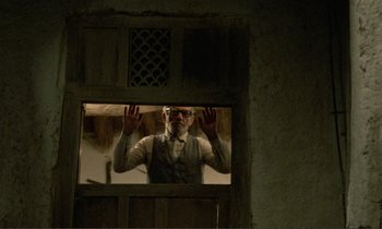Movie still from “Where Is the Friend's House?” (1987), directed by Abbas Kiarostami – An old man standing in front of an open window; Medium shot, Low angle