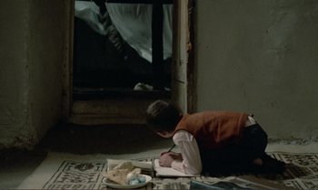 Movie still from “Where Is the Friend's House?” (1987), directed by Abbas Kiarostami – A young boy is writing in a notebook; Wide shot, High angle