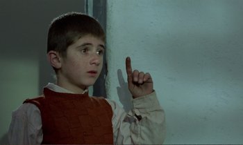 Movie still from “Where Is the Friend's House?” (1987), directed by Abbas Kiarostami – A young boy is pointing to the side of a wall; Close Up shot, High angle