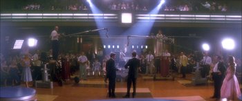 Movie still from “Where the Truth Lies” (2005), directed by Atom Egoyan – A group of men standing in front of microphones in a room; Wide shot, Over the shoulder angle