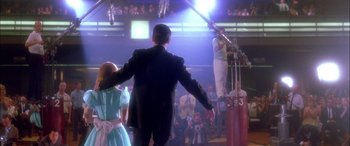 Movie still from “Where the Truth Lies” (2005), directed by Atom Egoyan – A man and a woman are standing in front of an audience; Wide shot, Low angle
