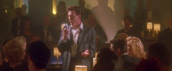 Movie still from “Where the Truth Lies” (2005), directed by Atom Egoyan – A man holding a microphone while standing in front of a crowd; Medium shot, Low angle