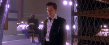 Movie still from “Where the Truth Lies” (2005), directed by Atom Egoyan – A man in a suit standing in front of lights; Medium shot, Low angle