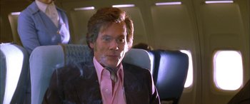Movie still from “Where the Truth Lies” (2005), directed by Atom Egoyan – A man sitting on a seat on an airplane smoking; Close Up shot, Low angle