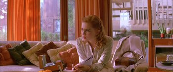 Movie still from “Where the Truth Lies” (2005), directed by Atom Egoyan – A woman sitting on top of a couch in a living room; Medium shot, Over the shoulder angle