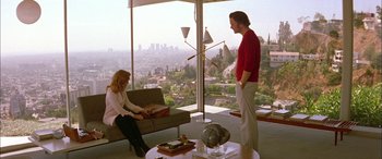 Movie still from “Where the Truth Lies” (2005), directed by Atom Egoyan – A man and a woman are sitting in a living room; Wide shot, Low angle